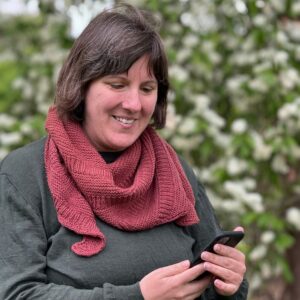 Vardagssjalen runt halsen på Johanna som tittar ner på sin mobil