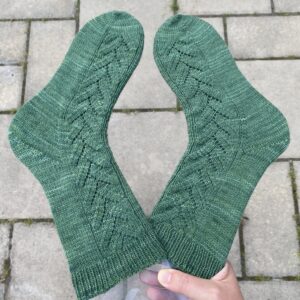 Gröna Branches sockar hålls över en grå bakgrund.