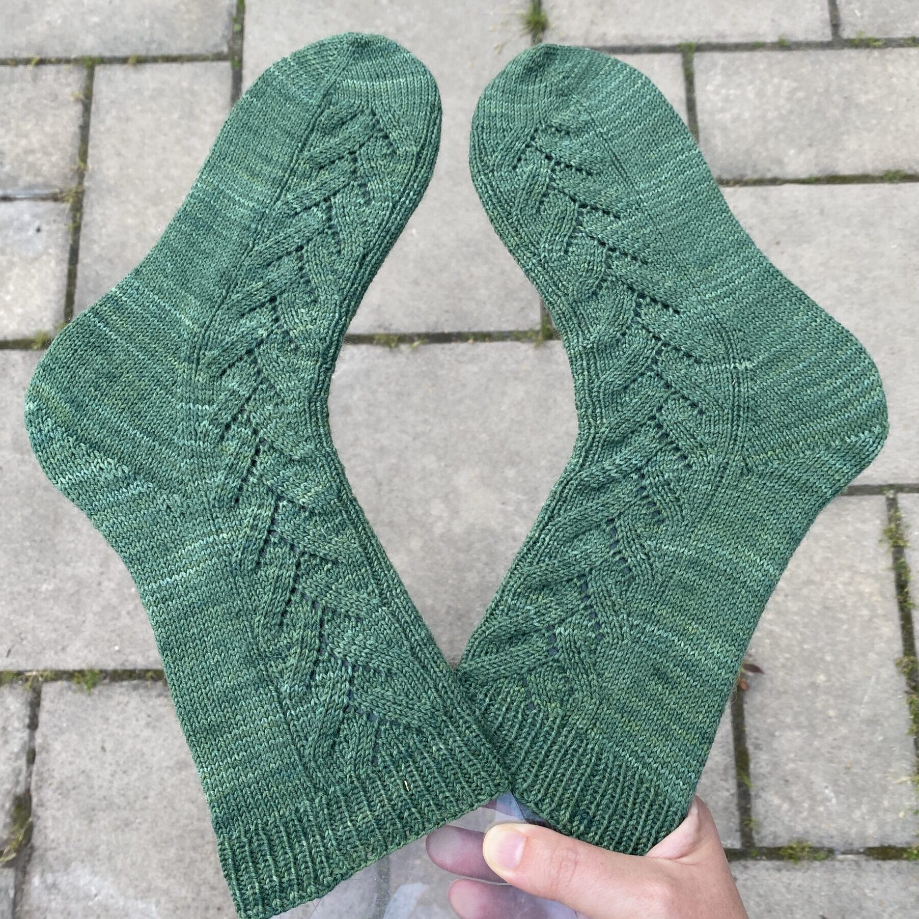 Gröna Branches sockar hålls över en grå bakgrund.