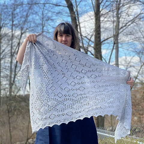 En ljusgrå spetsstickad sjal vajar i vinden.